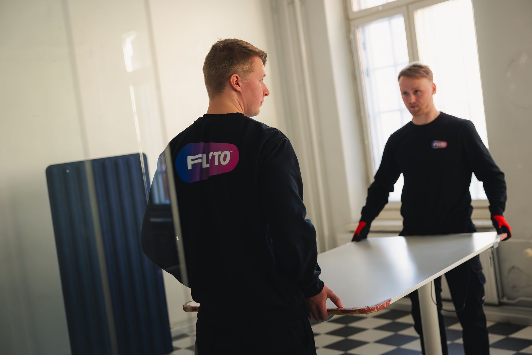 Flyton muuttaja muuttolaatikon kanssa auton edessä