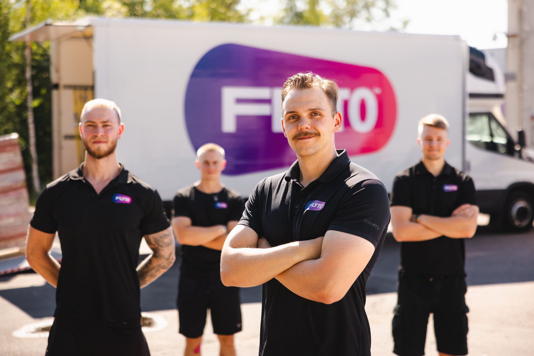 Flyton ammattitaitoinen muuttotiimi muuttoauton edessä